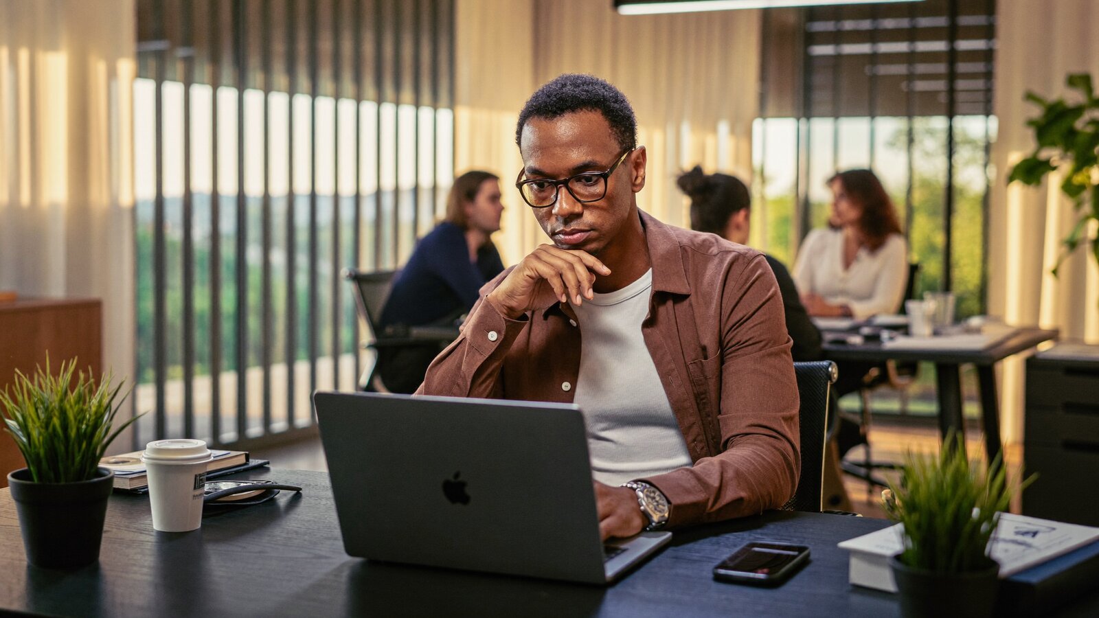 Confident Rwandan entrepreneur thinking about his business brand and domain name on a laptop in a modern Kigali co-working space