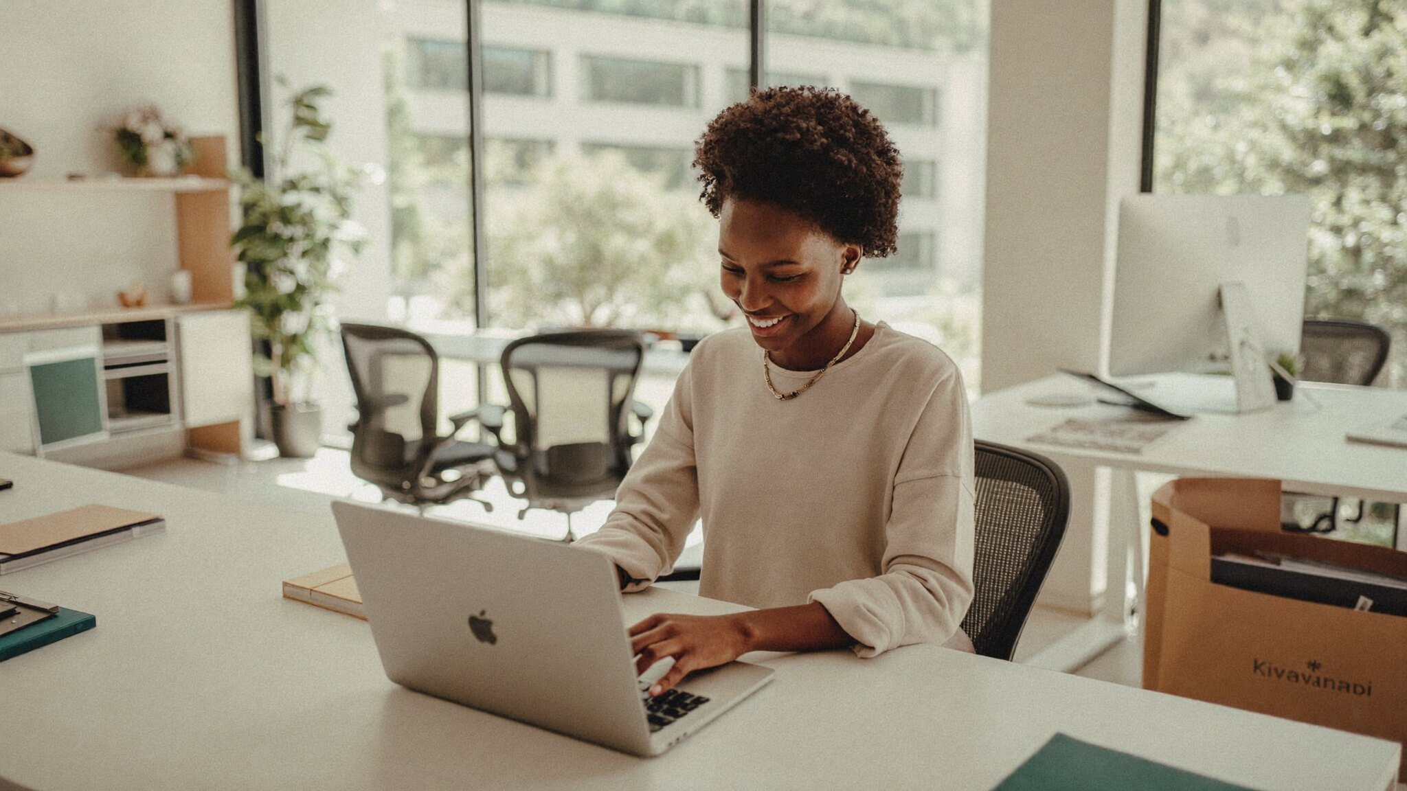 A young Rwandan businesswoman smiling while setting up her professional business email on a laptop in a bright modern Kigali office